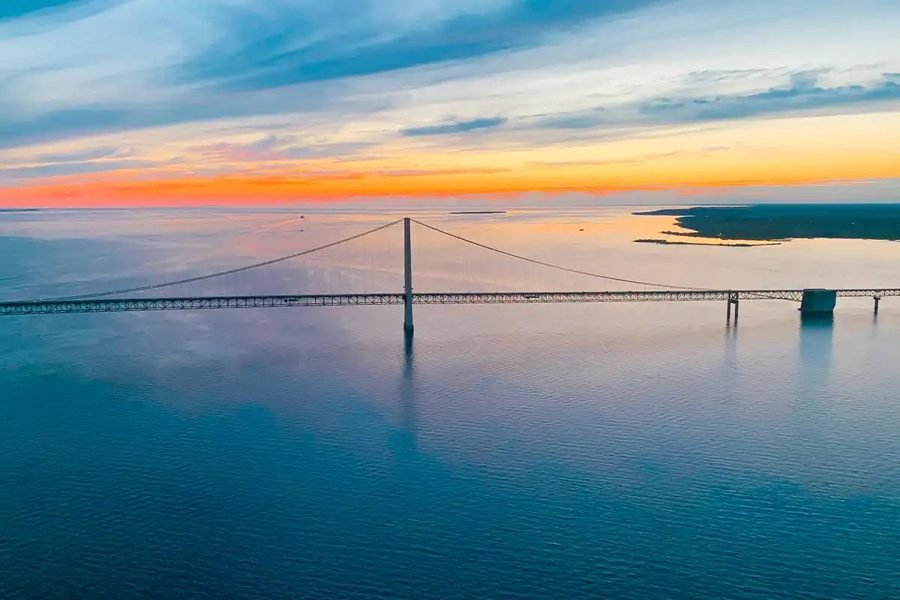 Aerial view of the Mackinac Bridge and water at sunset, seen from above