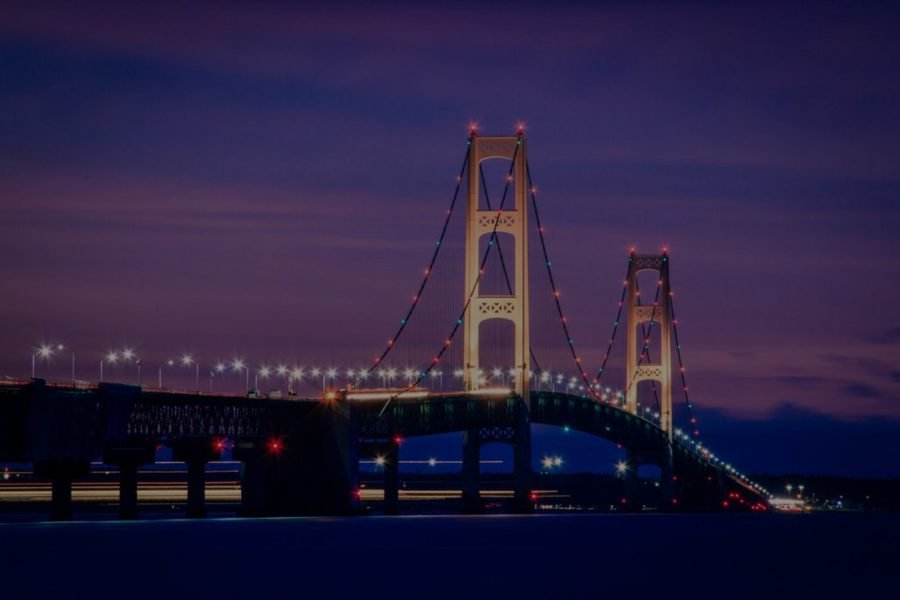 The Mackinac Bridge at dusk, lights coming on under a pink sky